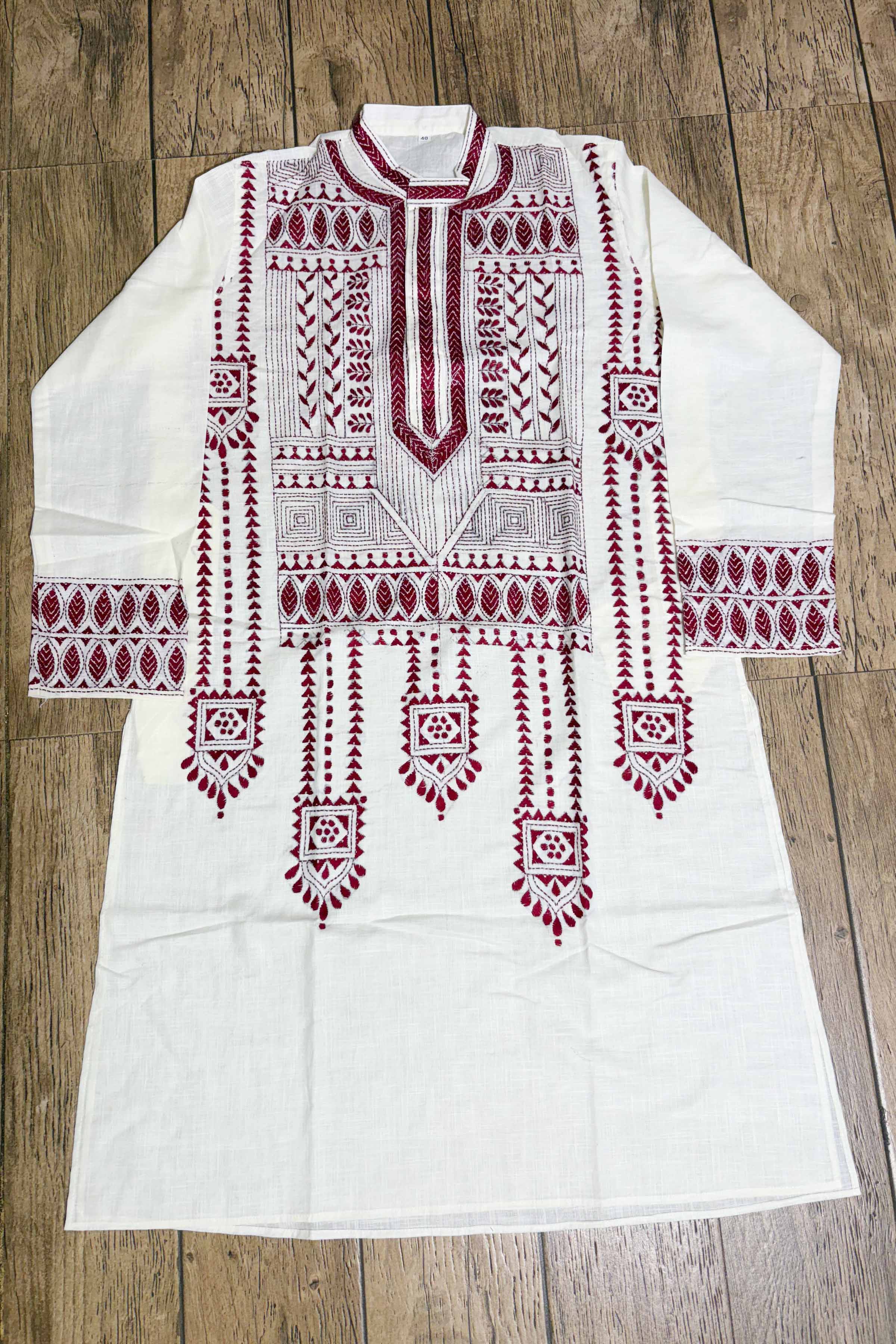 White embroidered kurta with red patterns on a wooden surface